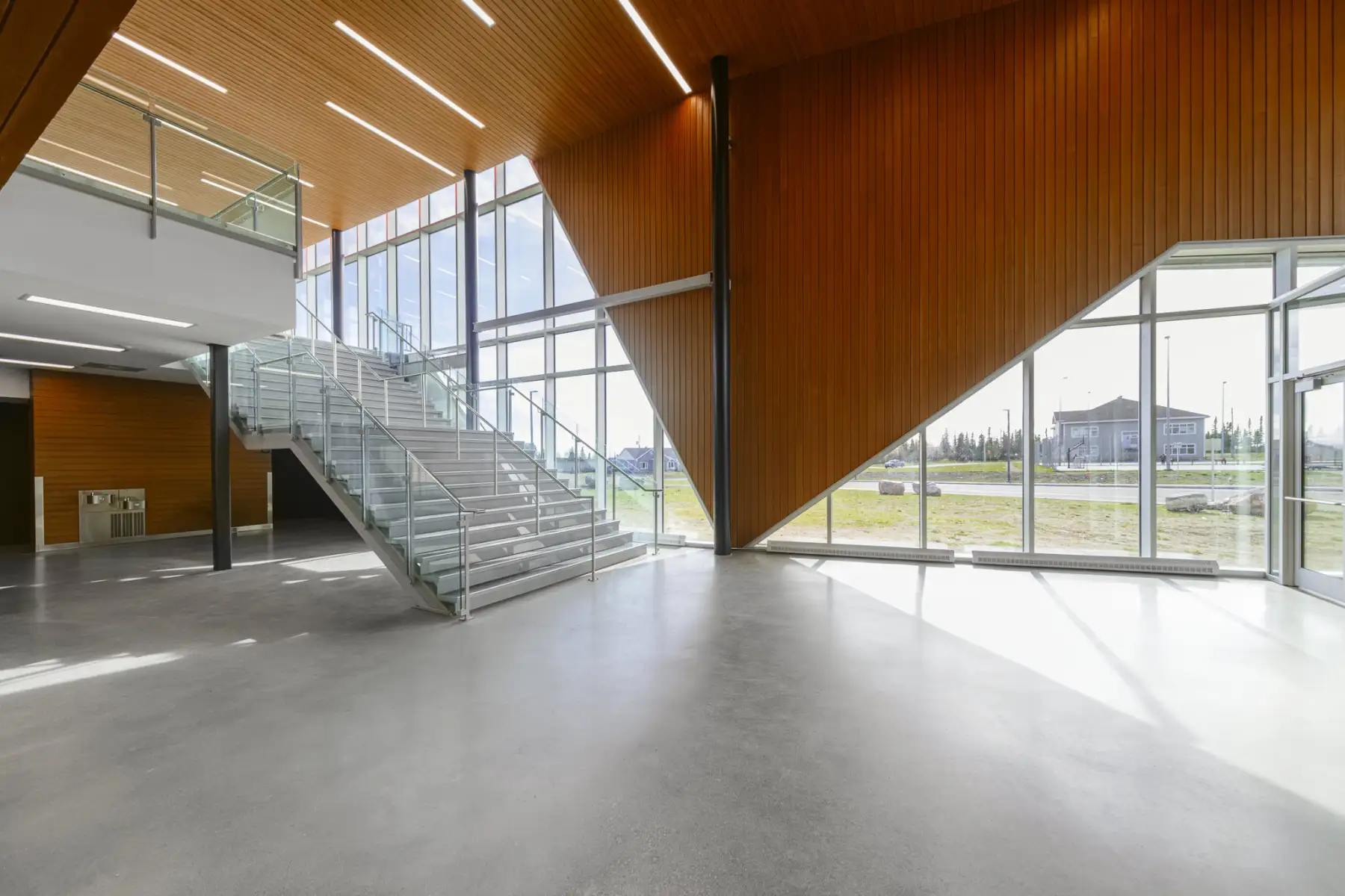 Entrée de l’aréna de Wemindji avec un escalier moderne et des murs en bois chaleureux.